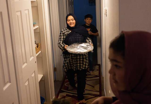 Woman carries a tray of food in a hallway